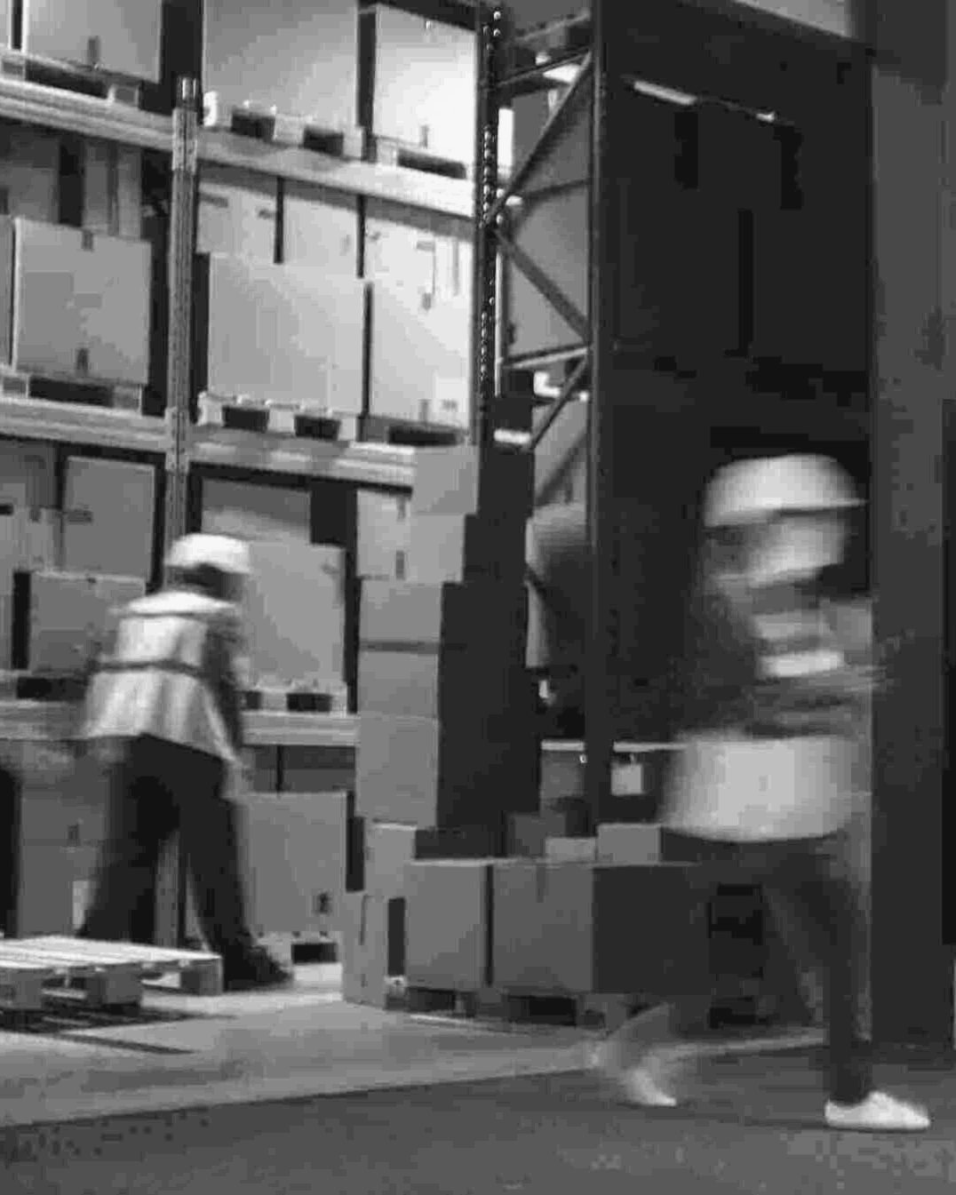 Warehouse staff moving cartons between racking and the dock door