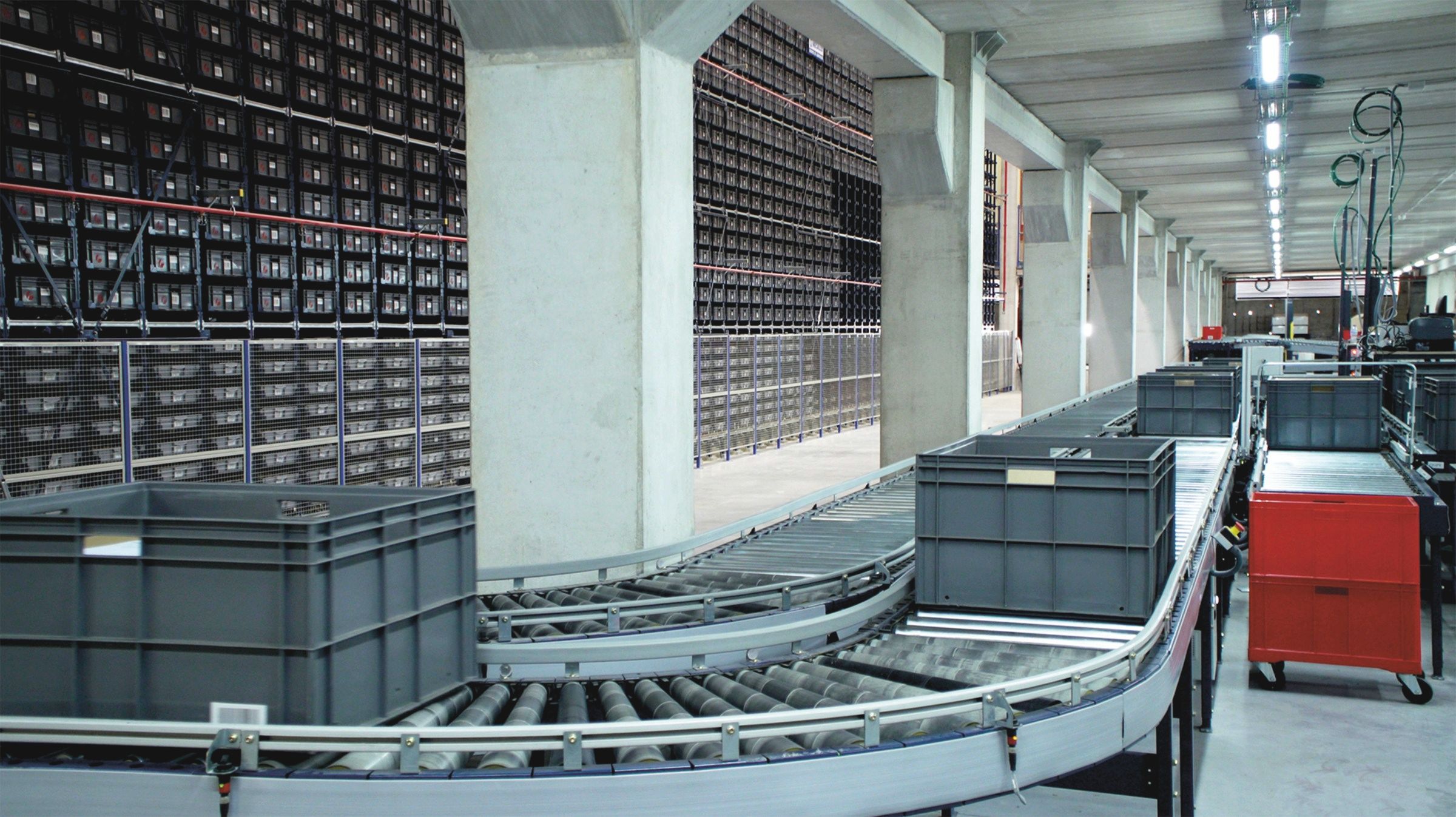 Totes on a conveyor loop beside a mini-load store